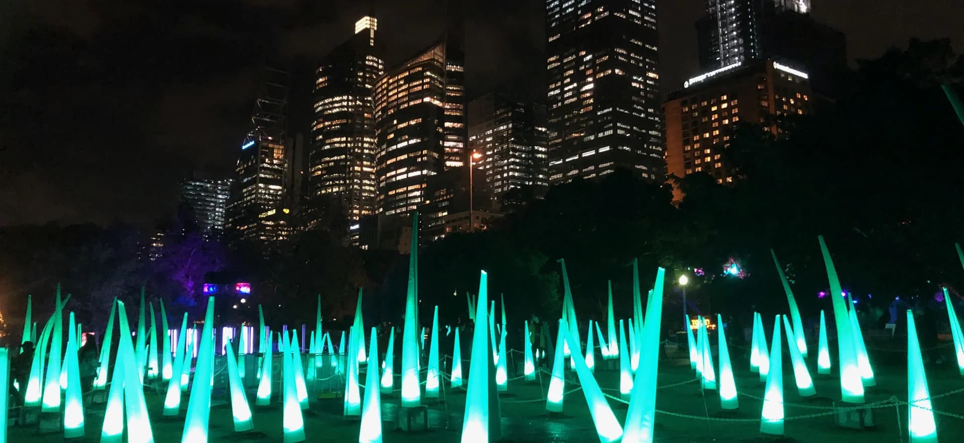 Sydney CBD skyline at night during Vivid, with turquoise light installations